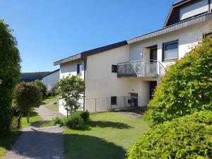 an apartment building with a balcony and a yard at Schwarzwaldblick F App 3 mit Pool in Schönwald