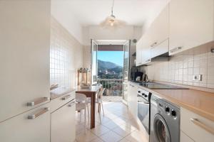 a kitchen with white cabinets and a table and a window at Maison Giovanna with garage parking in Rapallo