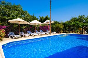 a swimming pool with chairs and umbrellas at Can Consul in San Juan Bautista