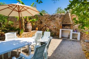 a table and chairs with an umbrella and a fireplace at Can Consul in San Juan Bautista