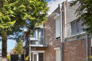 a brick house with a balcony and a tree at Apartment am Tor zu Hamburg in Neu Wulmstorf