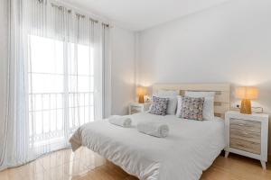 a white bedroom with a large bed with two windows at Beach Center Only 150 M Luxury in Fuengirola