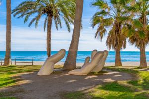 a sculpture of hands on a beach with palm trees at Beach Center Only 150 M Luxury in Fuengirola