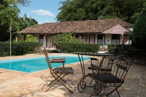 patio z krzesłami i stołem przy basenie w obiekcie Pousada da Bia w mieście Tiradentes