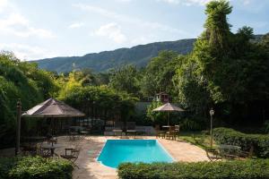 a swimming pool with chairs and tables and umbrellas at Pousada da Bia in Tiradentes