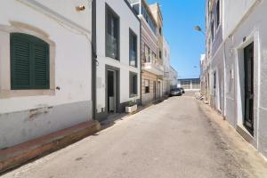 an empty alleyway between two buildings with a car in the distance at Casa Lopes in Fuzeta