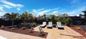a group of benches sitting in a courtyard with palm trees at Villa Adais in Playa Blanca