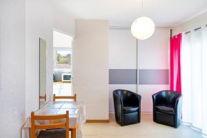 a dining room with a table and two black chairs at Les Mimosas - Appartement 08 in Cazaubon +12 photos