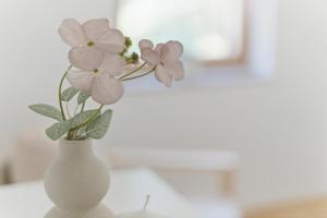 a white vase with flowers in it on a table at Mini Trenta in Soča