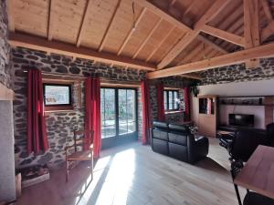 a living room with a stone wall and red curtains at Gîte La Forge Faverolles in Arcomie
