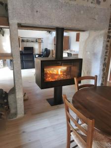 a fireplace in a living room with a table at Gîte La Forge Faverolles in Arcomie