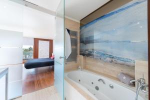 a bathroom with a tub and a painting on the wall at Marítimo 46 in Alcudia +21 photos