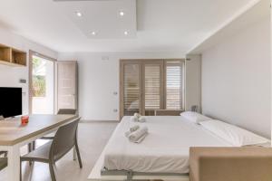 a white bedroom with a bed and a table and a desk at Appartamenti a 50 m dal mare in Torre San Giovanni Ugento