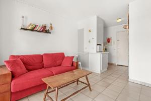 a living room with a red couch and a table at Appartement à deux pas de la mer in Fréjus