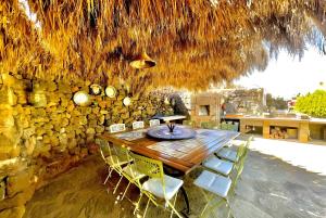 a dining room with a table and chairs and a stone wall at Dammuso Civulia Pantelleria in Pantelleria