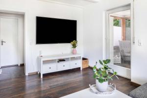 a white living room with a flat screen tv on a wall at Haus Albi in Waldkirch +33 photos