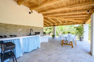 an outdoor kitchen with a table and a wooden ceiling at Foxi lioni in Tertenìa