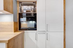 a kitchen with white cabinets and a black oven at Auszeit Schwarzwald in Furtwangen