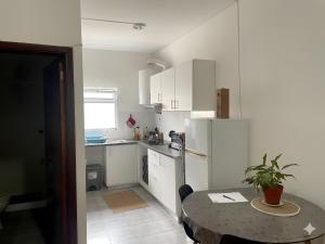 a kitchen with a table and a refrigerator and a table and a room at apartment near the airport in Ponta Delgada +6 photos
