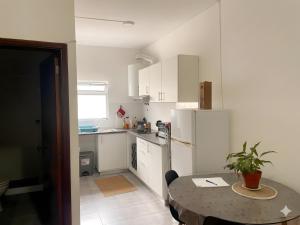a small white kitchen with a table and a dining room at apartment near the airport in Ponta Delgada