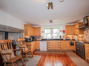 a kitchen with wooden cabinets and chairs and a window at Achnagonlin House in Grantown on Spey