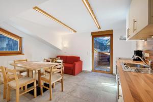 a kitchen and dining room with a table and a red couch at New - Steinhof Val di Mezzo in Val di Mezzo
