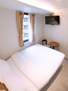 a large white bed in a room with a window at D-Haus Hostel Dongdaemun in Seoul