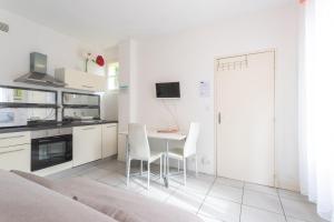 a white kitchen with a table and chairs at Le Béout rez-de-jardin in Lourdes