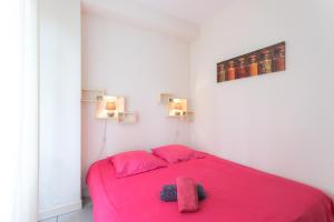 a bedroom with a pink bed with two towels on it at Le Béout rez-de-jardin in Lourdes