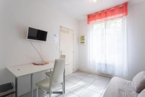 a small room with a desk and a tv on the wall at Le Béout rez-de-jardin in Lourdes