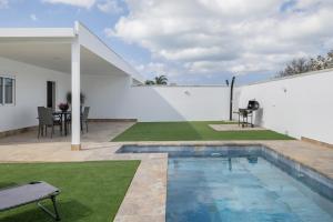 a backyard with a swimming pool and a white wall at Villa Laruma in Cádiz