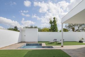 a garden with a swimming pool and a white wall at Villa Laruma in Cádiz