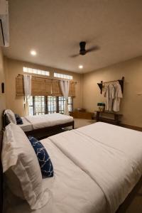 a bedroom with two beds and a ceiling fan at Lilo House, Thaimueang Beach in Thai Muang