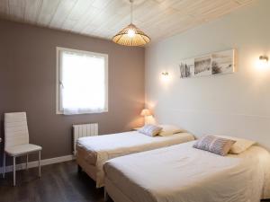 two beds in a room with a chair and a window at Gîte Pors Mabo in Trébeurden