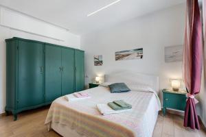 a bedroom with a bed with green cabinets and towels at Casa Lago Vicky in Omegna