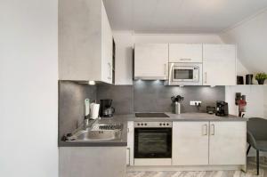 a kitchen with white cabinets and a sink and a microwave at Ferienwohnung City in Emden