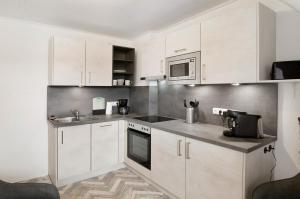 a kitchen with white cabinets and a microwave at Ferienwohnung City in Emden +16 photos