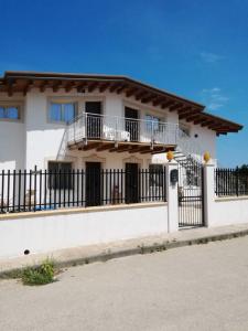 a white house with balconies and a fence at Casa Vacanza Brucoli Mare 2 in Brucoli