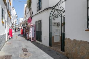 a narrow alley with a white building and a store at Casa Paqui Bustos 1 in Conil de la Frontera