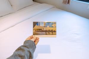 a hand holding a picture on a bed at D-Haus Hostel Dongdaemun in Seoul +70 photos