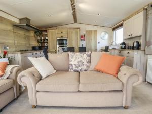 a living room with a couch and a kitchen at Number 6 - Sandy Beach Holiday Park in Norwich