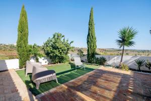 a patio with chairs and a lawn with trees at Casa Papaya in Vila Nova De Cacela