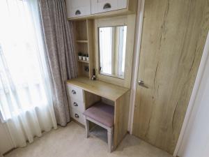 a dressing table with a mirror and a chair next to a window at Number 6 - Sandy Beach Holiday Park in Norwich +22 photos