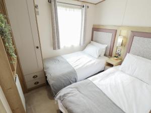 two beds in a small room with a window at Number 6 - Sandy Beach Holiday Park in Norwich