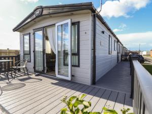 a house with a large deck with a patio at Number 6 - Sandy Beach Holiday Park in Norwich