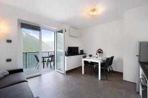a living room with a table and a kitchen with a balcony at Appartamento 8 Il Tornante in Nesso