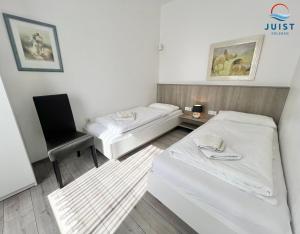 a small room with two beds and a chair at Haus Insa 145 - Ferienwohnung elf in Juist