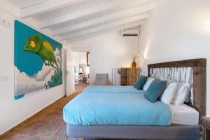 a bedroom with a blue bed and a painting on the wall at Casa Papaya in Vila Nova De Cacela