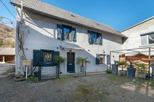 a white house with blue shuttered windows and plants at Les Écrins de Campan in Campan