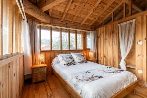 a bedroom with a bed with wooden walls and windows at Villa Chan-Ly in Lacanau